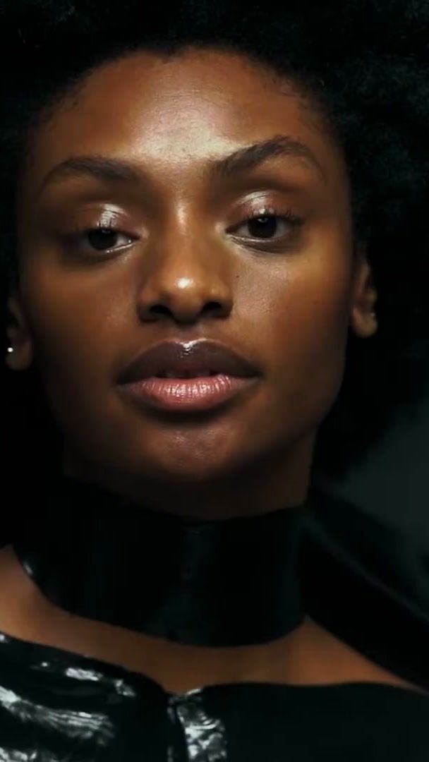 Model with bare glowing skin and a 111SKIN neck mask on black satin