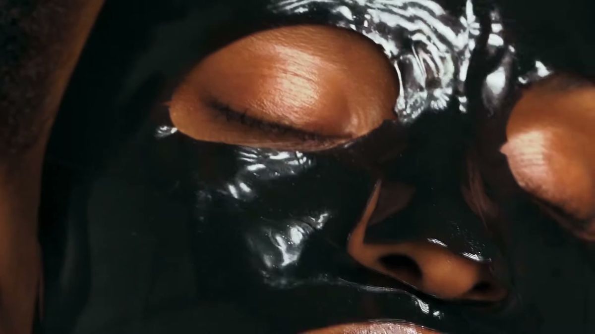 Close-up of a glossy black 111SKIN face mask over a closed eye