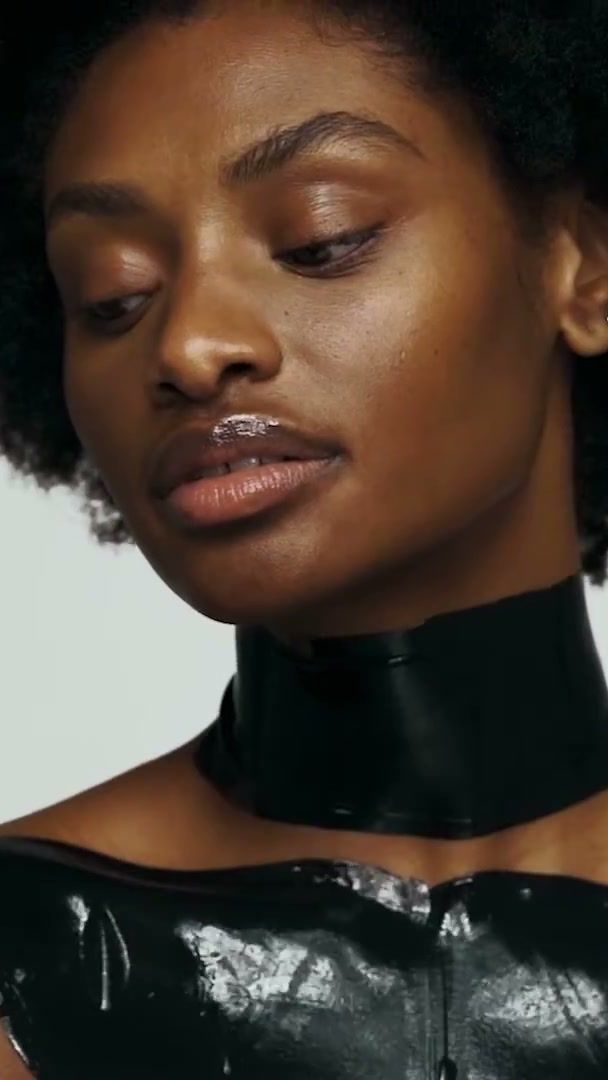 Model in a black 111SKIN neck and chest mask against a pale grey backdrop