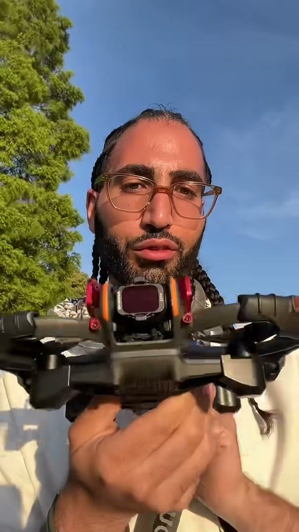 DJI Avata 2 held up to camera with orange bumper guards and a lens guard fitted