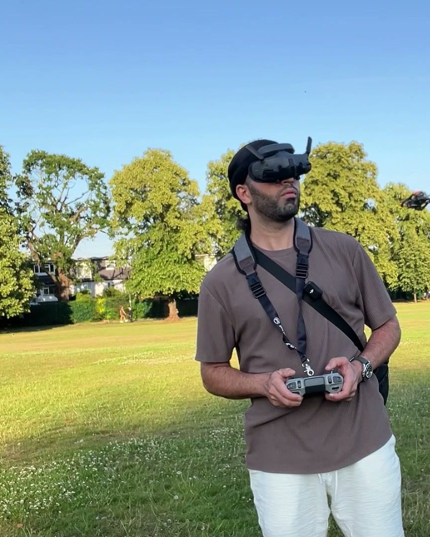 FPV pilot wearing DJI goggles and holding the remote in a London park