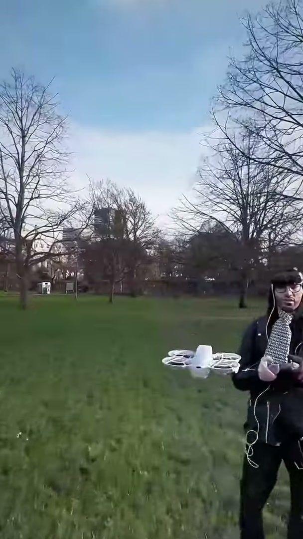 Pilot in FPV goggles holding a white DJI Neo in a London park
