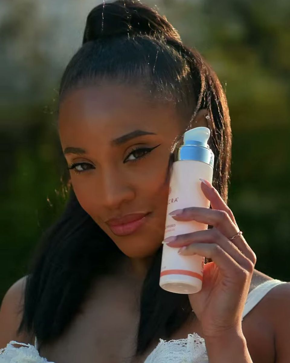 Skincare creator holding a Seacra bottle by her face on the beach, vertical social content