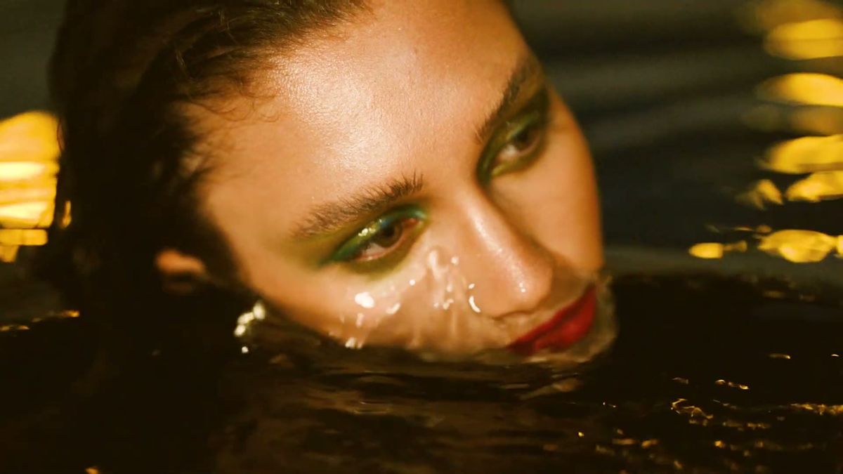 Wet skin close-up with green eyeliner and water droplets