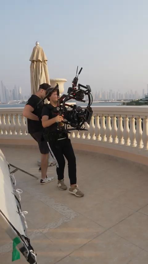 Camera operator with a gimbal rig on a terrace above the Dubai skyline during the Damas x Dome shoot