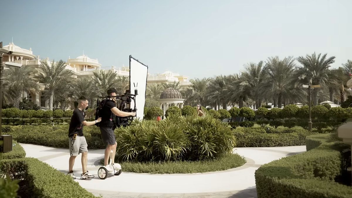 Camera crew moving a stabilised rig through a palace garden during a Damas campaign shoot in Dubai
