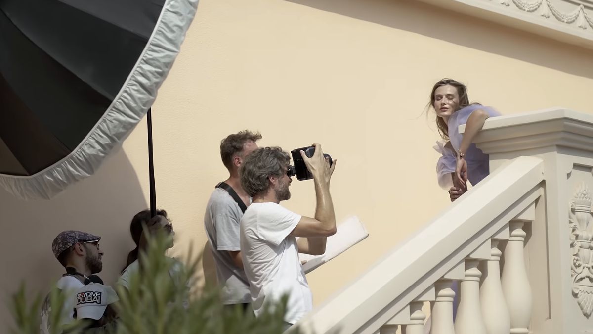 Stills photographer and team shooting a model on a palace staircase, Damas behind the scenes