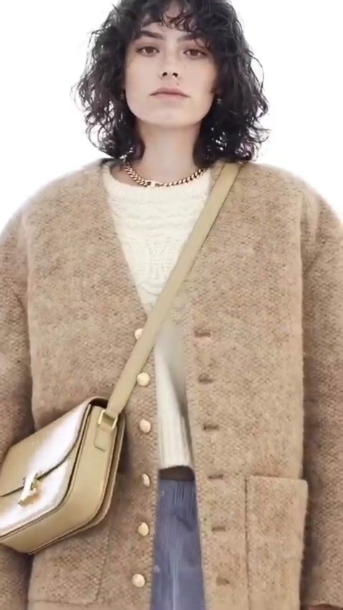Model in a Celine boucle cardigan with a gold shoulder bag