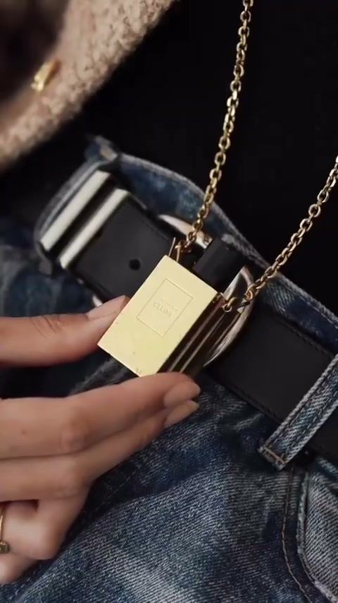 Detail of a gold Celine tag on a belt and jeans