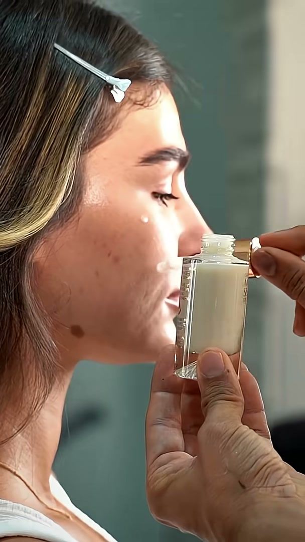 Make-up artist applying foundation from the bottle during prep on set