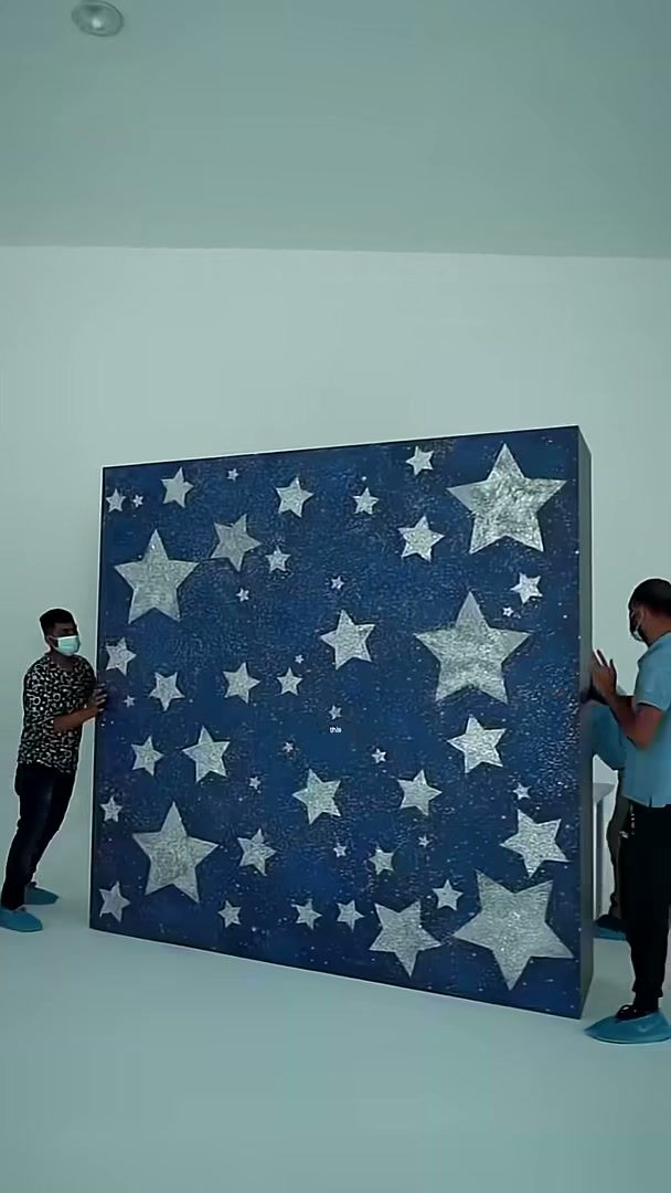 Crew moving a large starry blue backdrop flat in a white studio