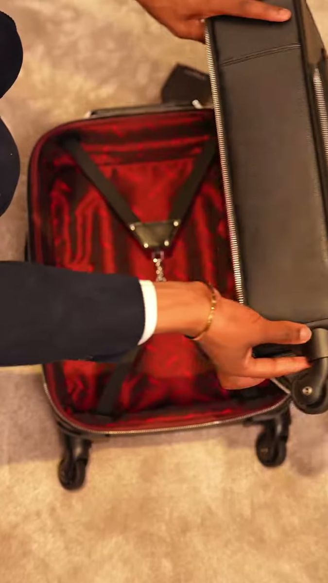 Hands packing an open suitcase with a red silk lining