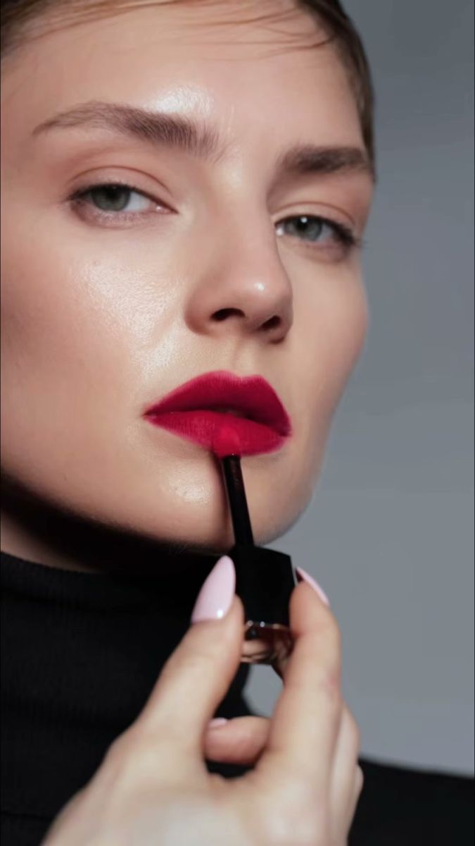 Model applying a red liquid lipstick against a grey backdrop, Waterproof beauty film