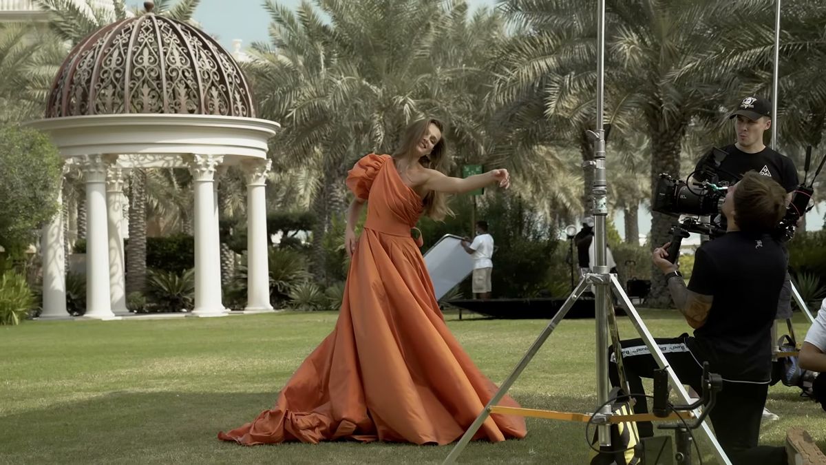 Crew filming a model in an orange gown in a Dubai palace garden for Damas Jewellery