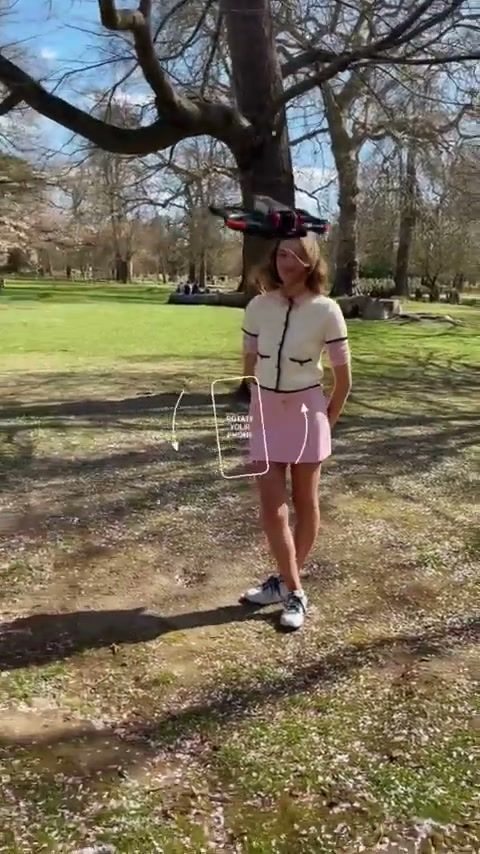 Model walking through a park during an FPV drone fashion shoot