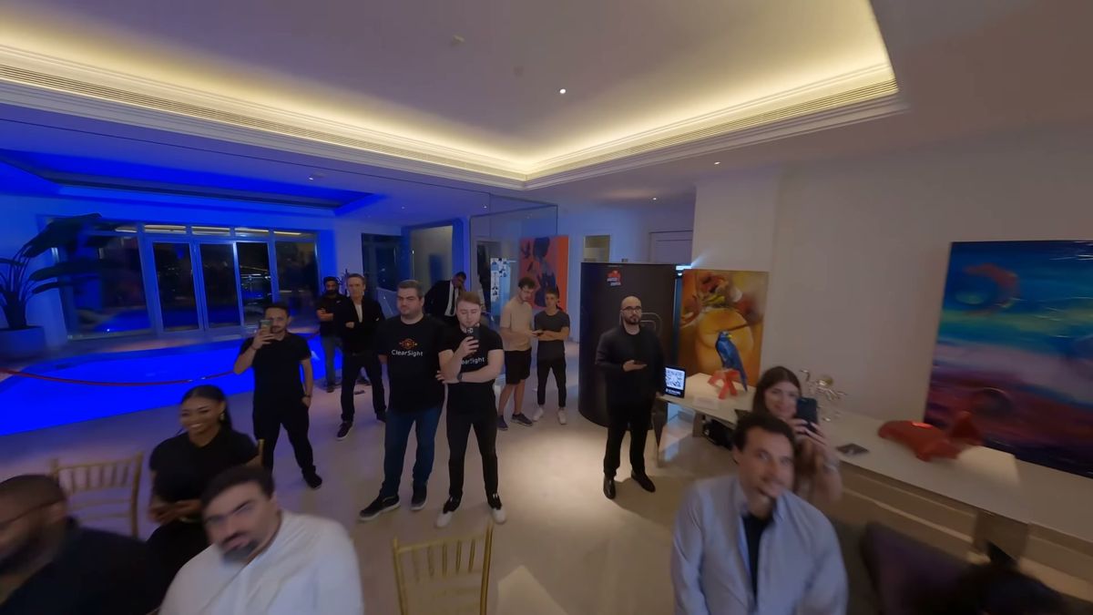 Guests watching an FPV drone fly through a blue-lit room at a Dubai event