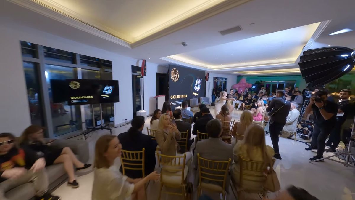 FPV drone view over a seated audience with a camera crew and a large light at a Dubai event