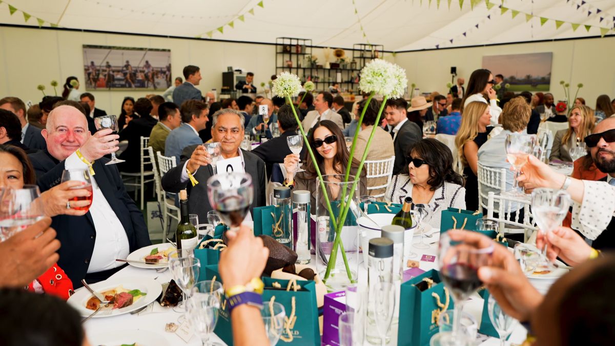 Guests raising glasses at lunch in the hospitality marquee at Polo in the Park, London