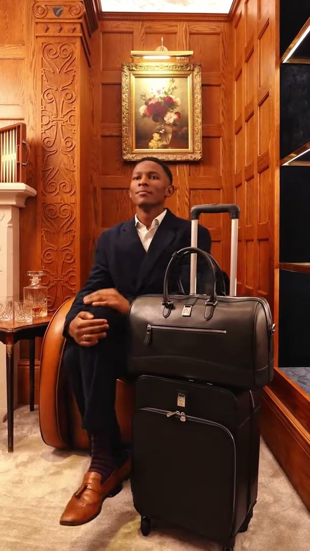 Model seated with Aspinal of London luggage in a wood-panelled room