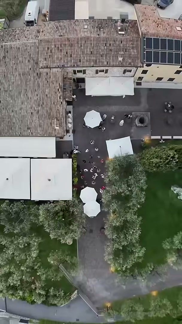 Top-down drone view of a wedding courtyard with white umbrellas