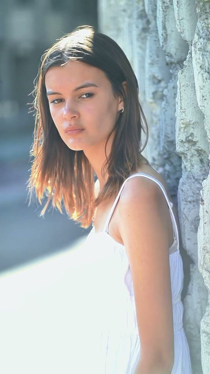 The same model with still hair, backlit against a stone wall