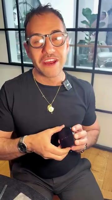 Make-up artist in glasses talking to camera while holding a compact, expert-style video