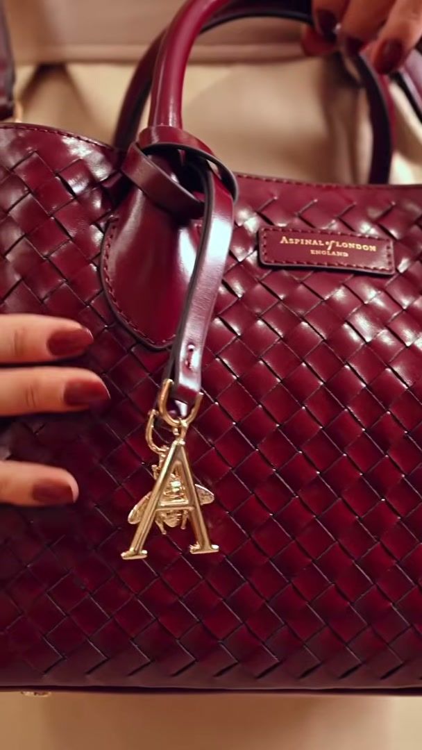 Gold A charm hanging from a burgundy woven leather Aspinal of London tote