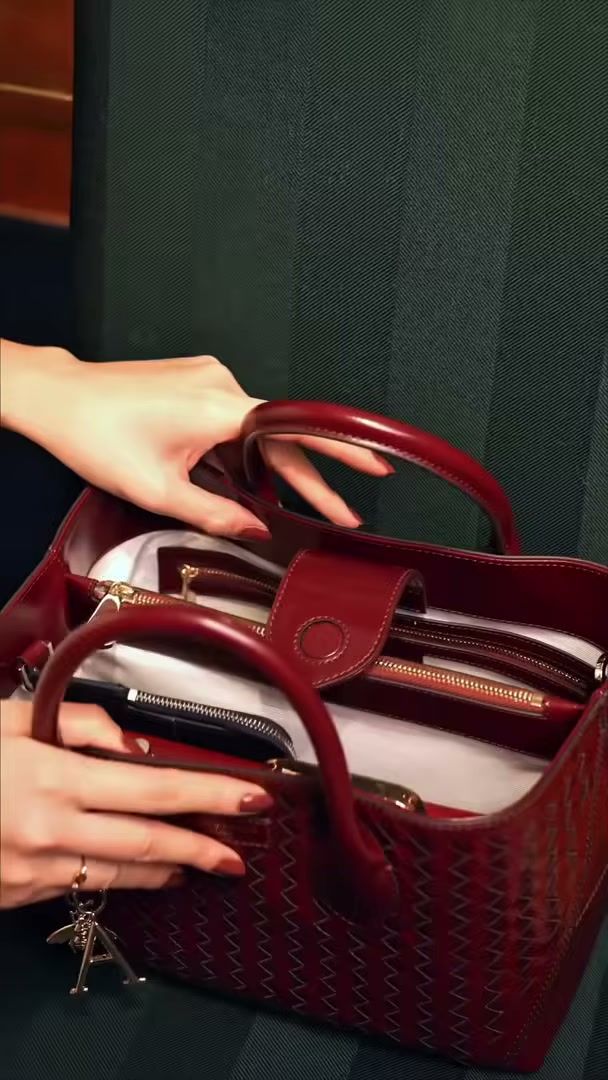 Hands opening an Aspinal of London tote to show the gold zip and the interior