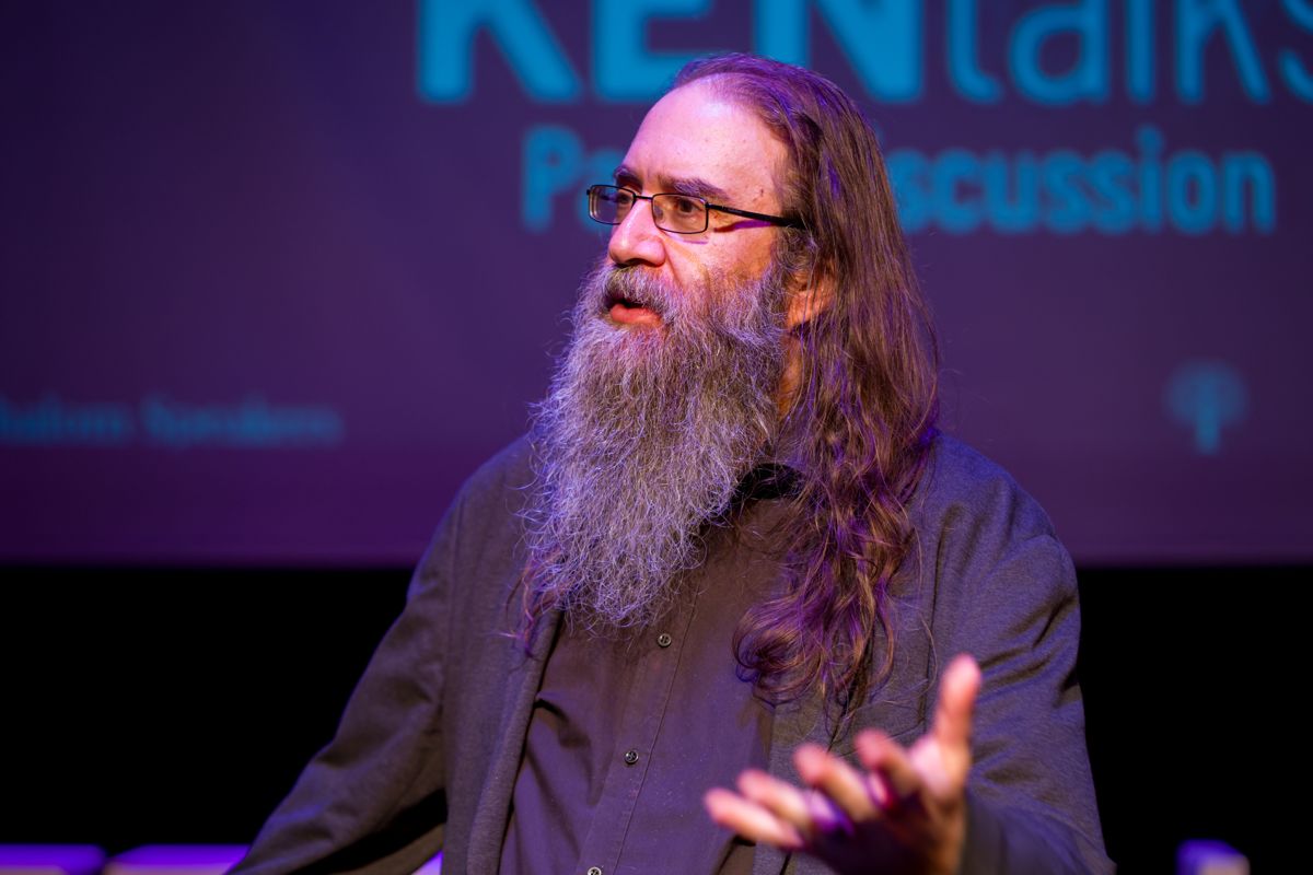 Panellist gesturing mid-answer in front of the KEN Talks Panel Discussion screen