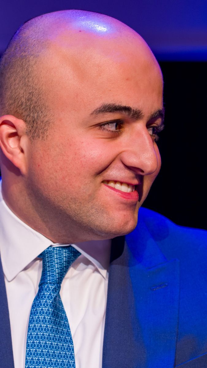 Panellist in a blue suit smiling on stage at KEN Talks