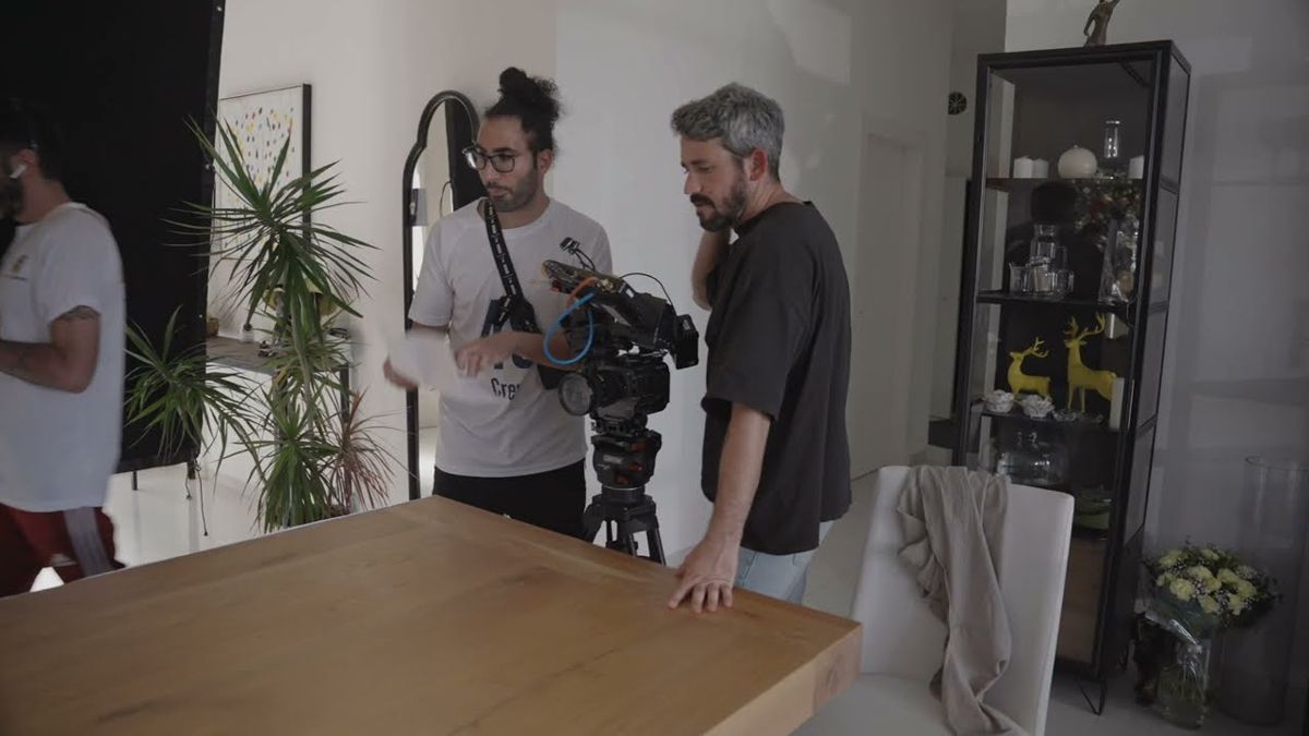 Behind the scenes of the KickOff commercial: crew with a cinema camera on a tripod by the dining table