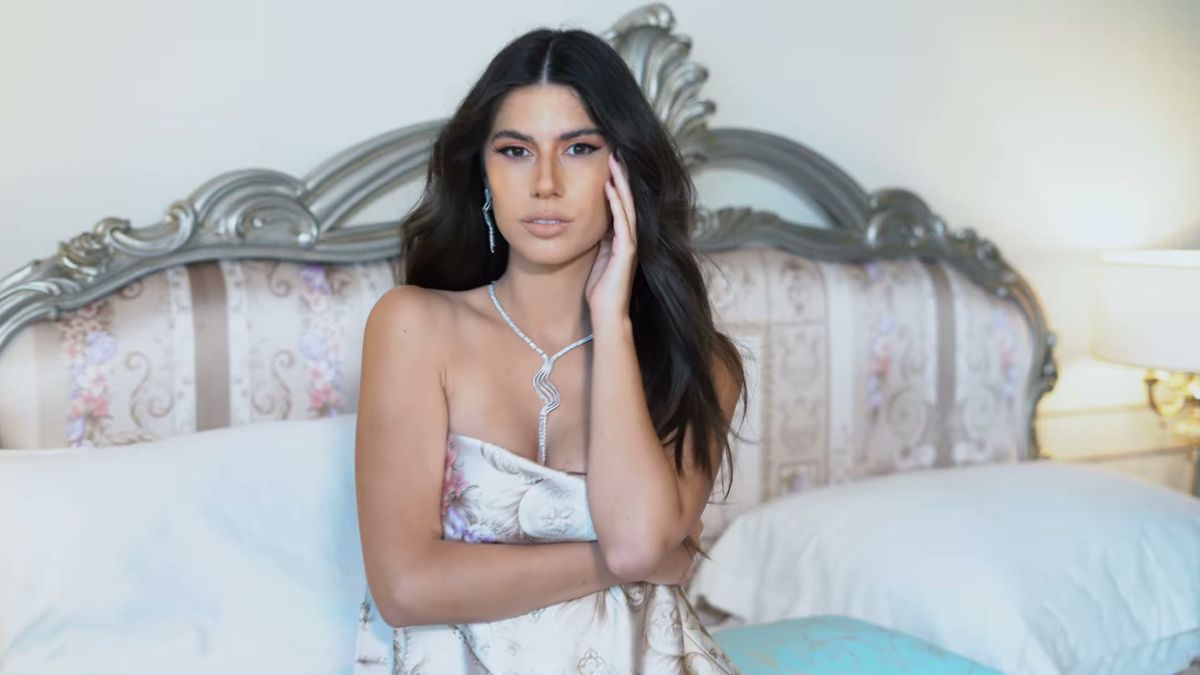 Model sitting on an ornate hotel bed wearing a necklace, L'Officiel Baltic