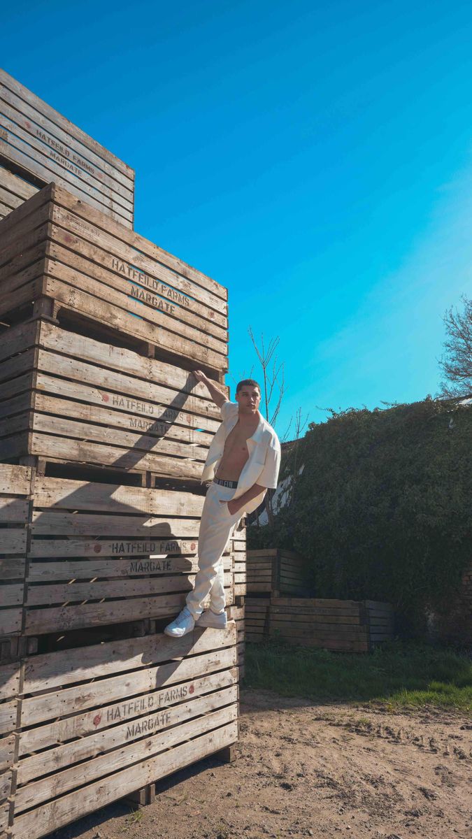 Model standing on stacked wooden farm crates in Kent, shot from a low angle