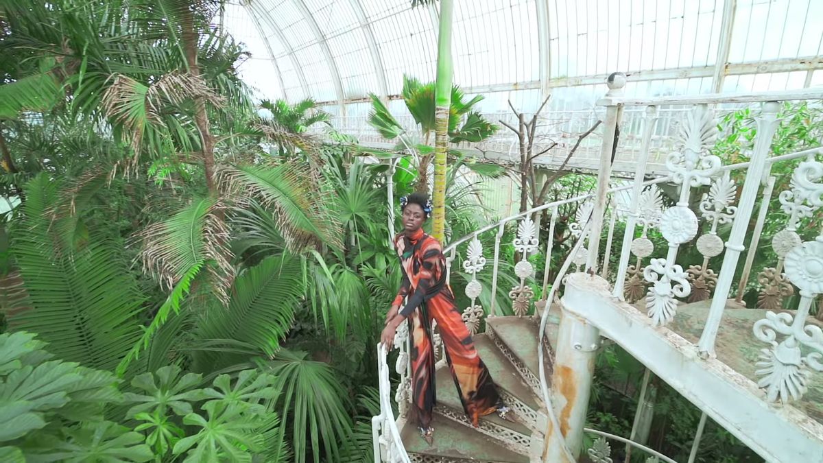 Model on a white iron staircase inside a Kew Gardens glasshouse during a fashion shoot