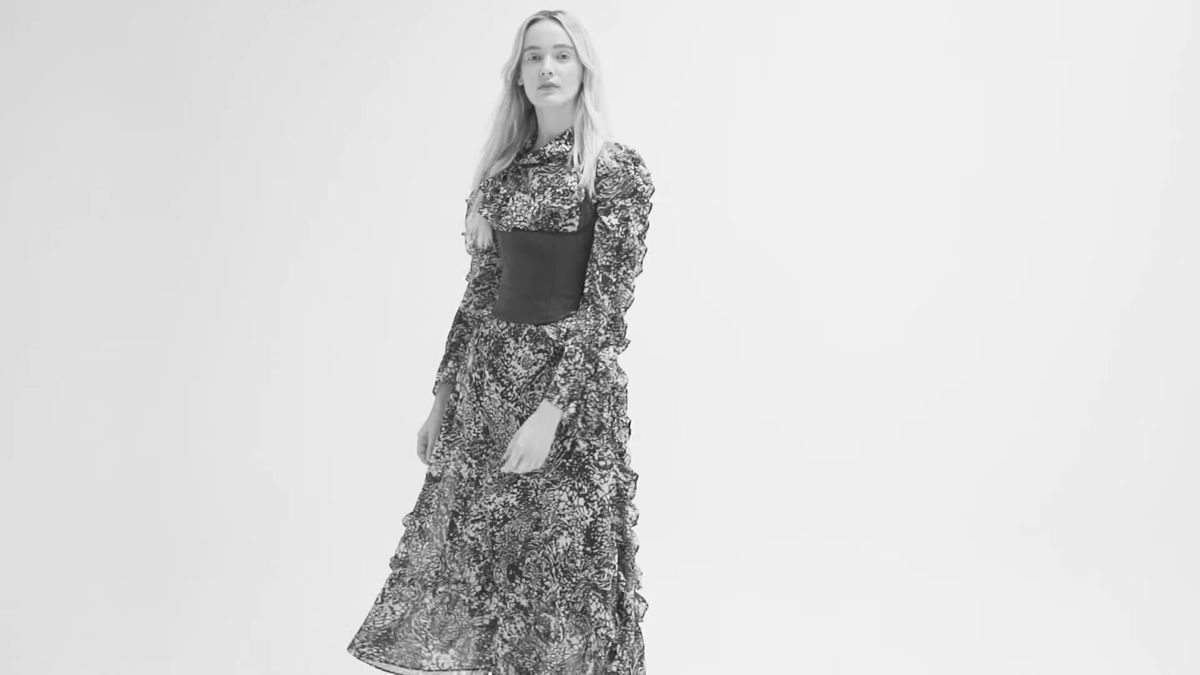 Full-length black and white shot of a model in a printed dress in a white studio