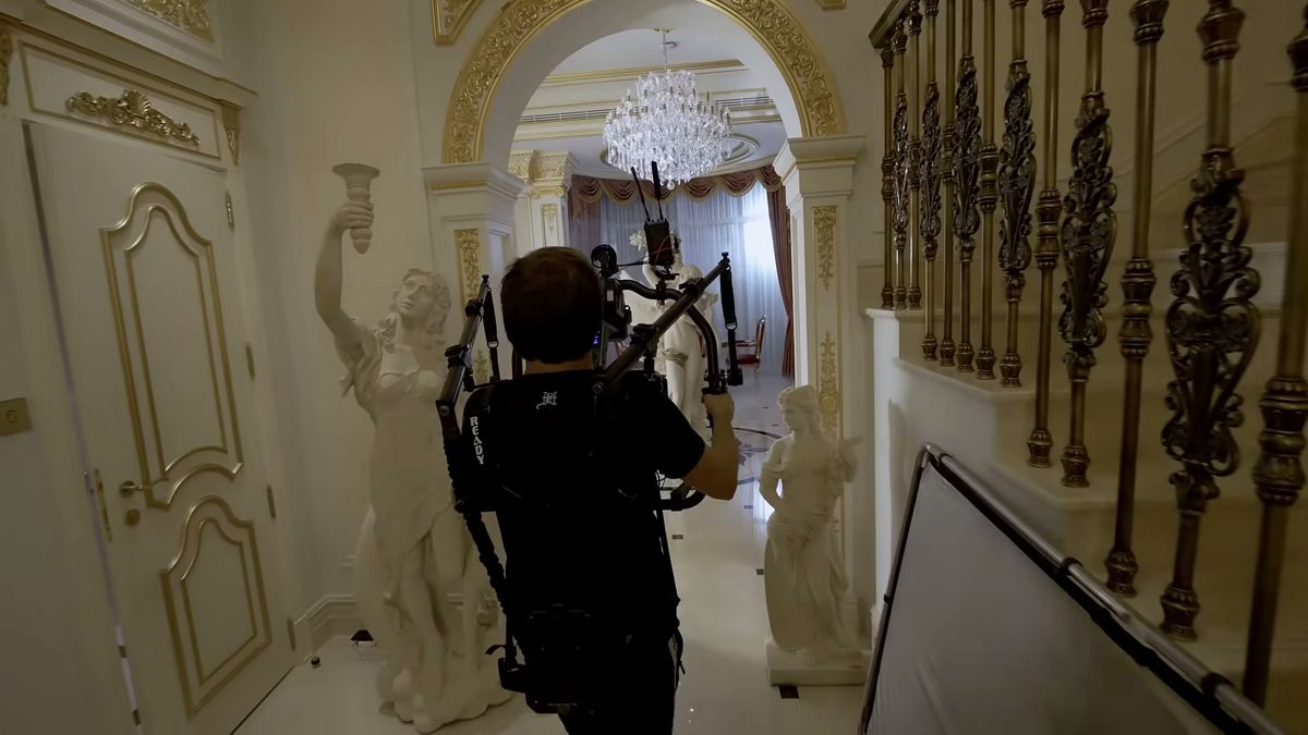 Steadicam operator walking through a gilded hallway with marble statues on the Damas campaign shoot