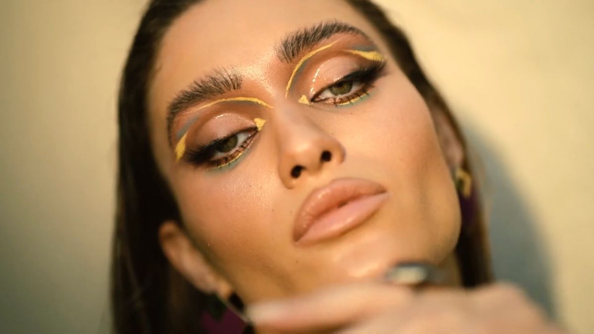 Graphic gold eyeliner and glossy skin in warm low sun, beauty shoot in Dubai