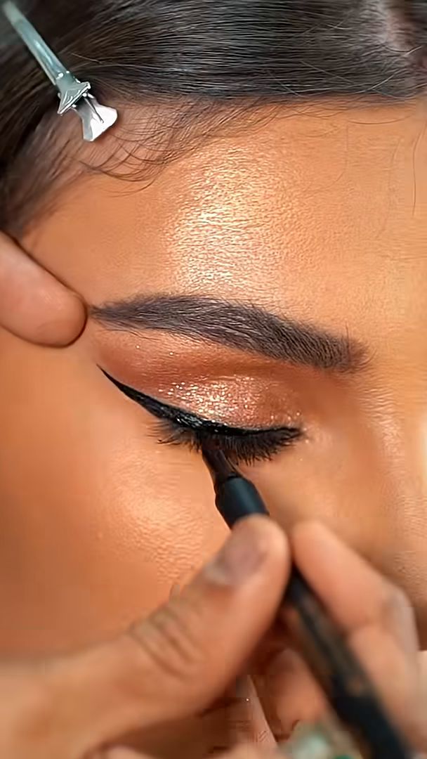 Winged eyeliner drawn over a shimmer lid in close-up