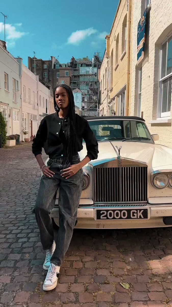 Model in black leaning on a vintage car in a cobbled London mews, full length test shot