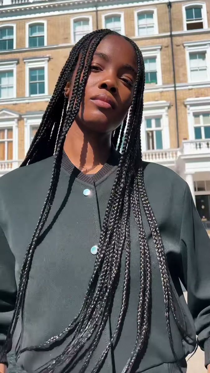Model with long braids in a grey jacket, portrait in bright sun in front of white London townhouses