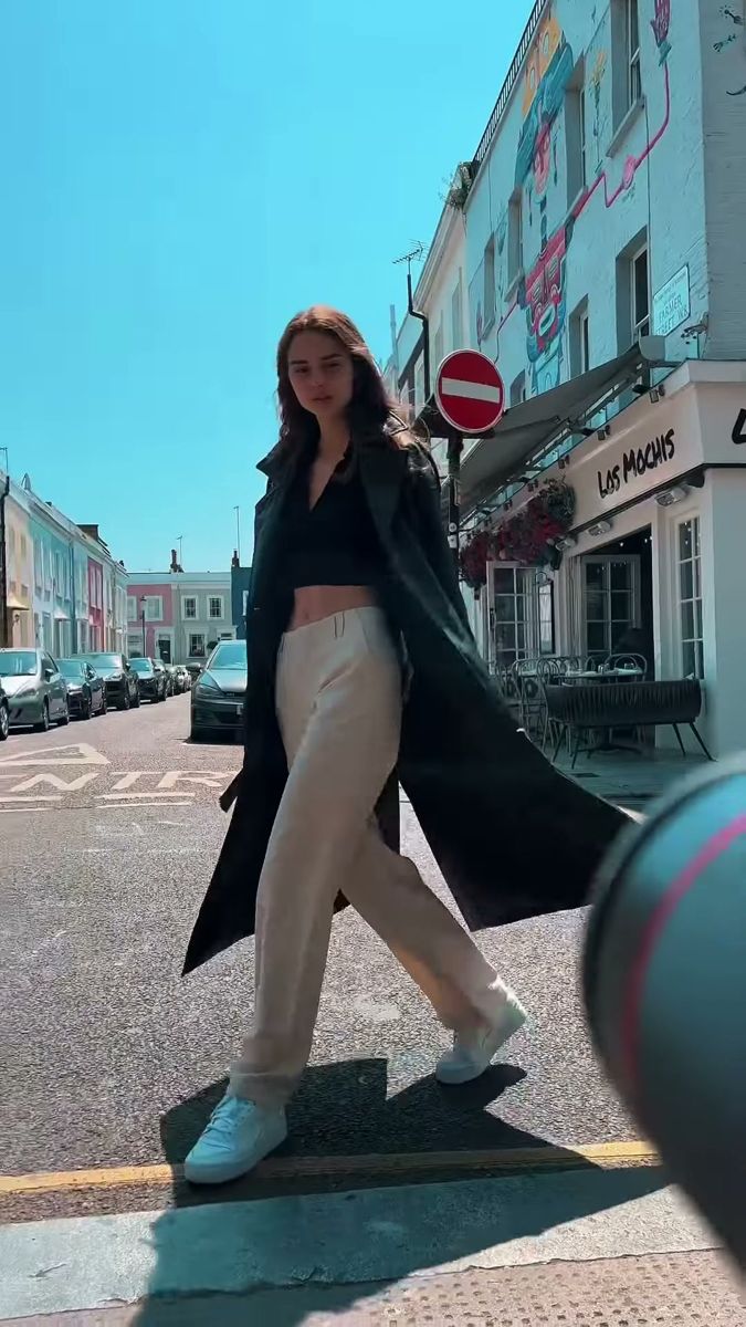 Low angle frame of a model walking towards the lens on a sunny London street
