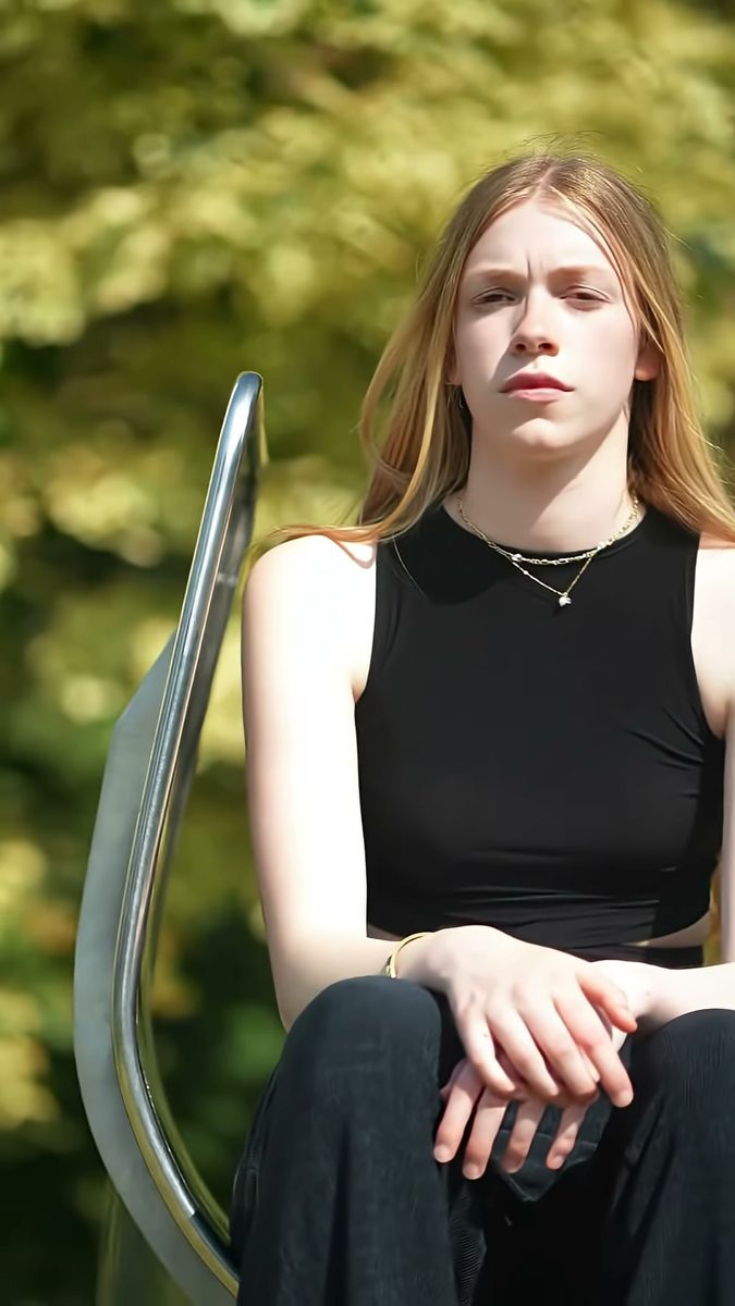New face model seated on a metal slide in a London park, natural light test