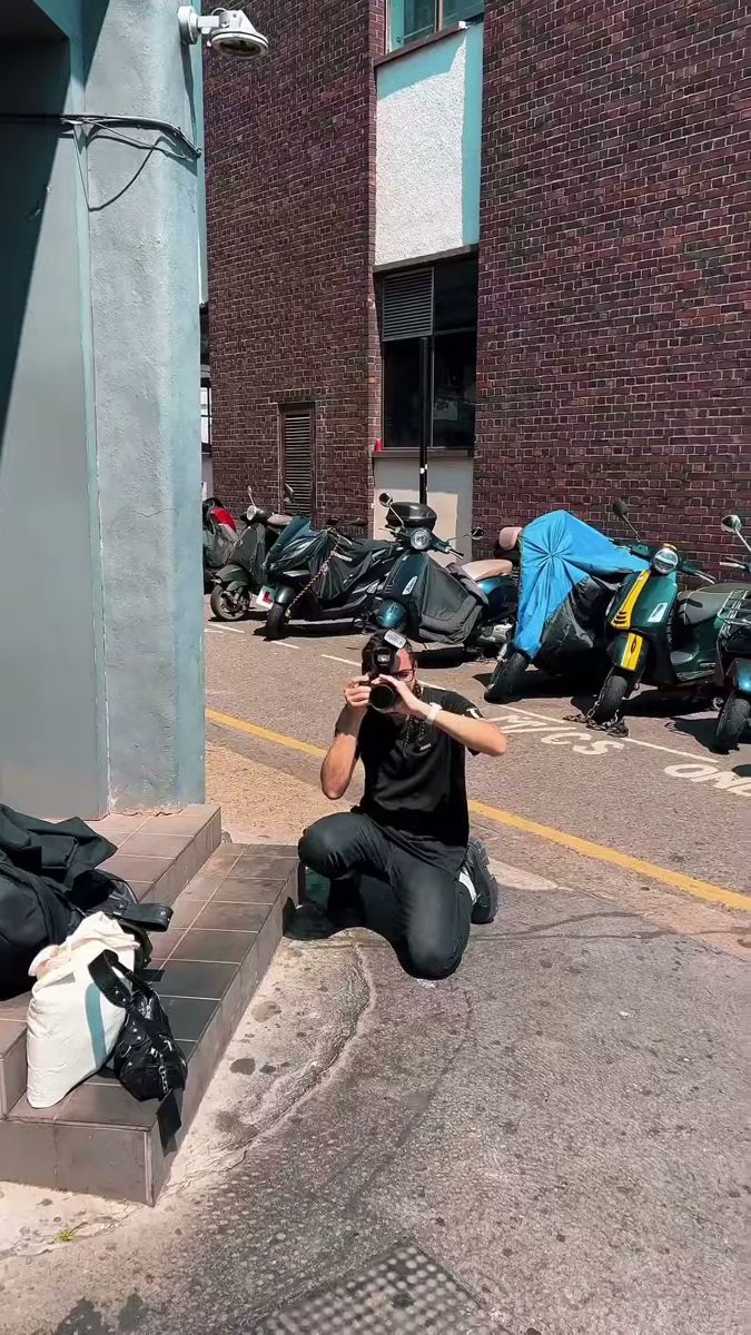 Photographer kneeling on a London pavement with a camera, behind the scenes of a model test