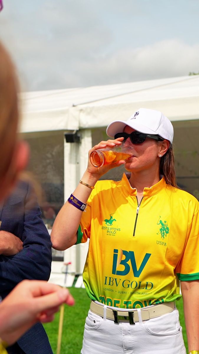 IBV Gold Team Cape Town player in a branded shirt having a drink pitchside at Polo in the Park