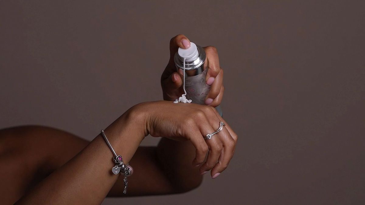 Seacra bottle pumping product onto the back of a hand against a warm grey background