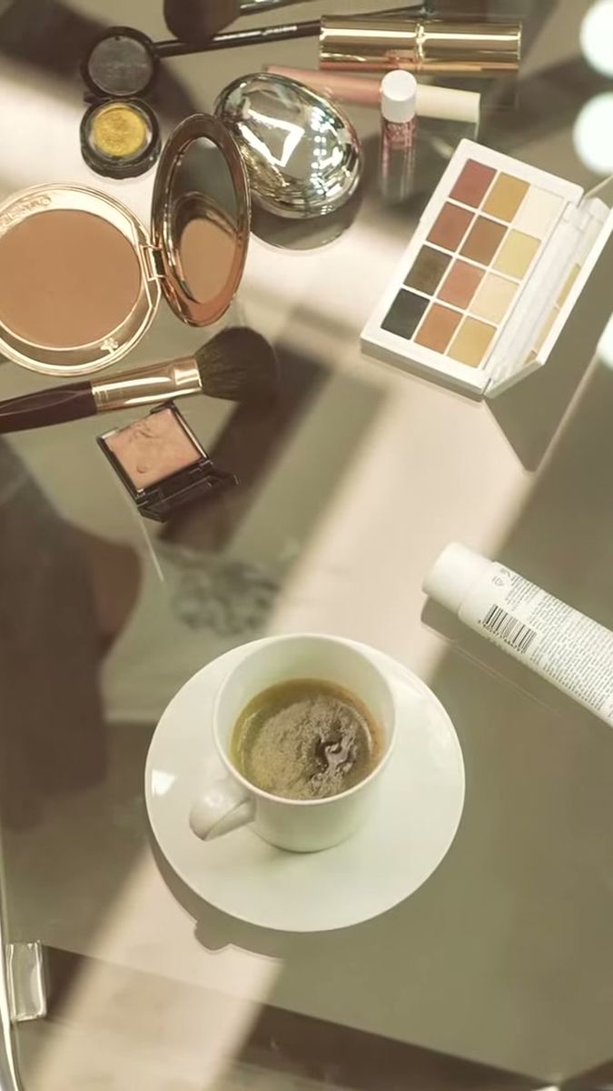 Overhead view of a make-up table with palette, powder and coffee beside the mirror lights, vertical