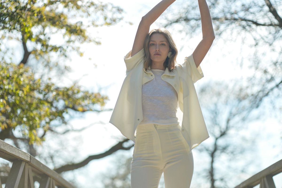 Alice stretches her arms above her head on a footbridge against the sky, movement on a model test shoot