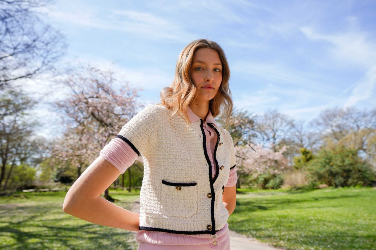Alice in a cream jacket and pink skirt, hand on hip under spring blossom and blue sky, Richmond test shoot