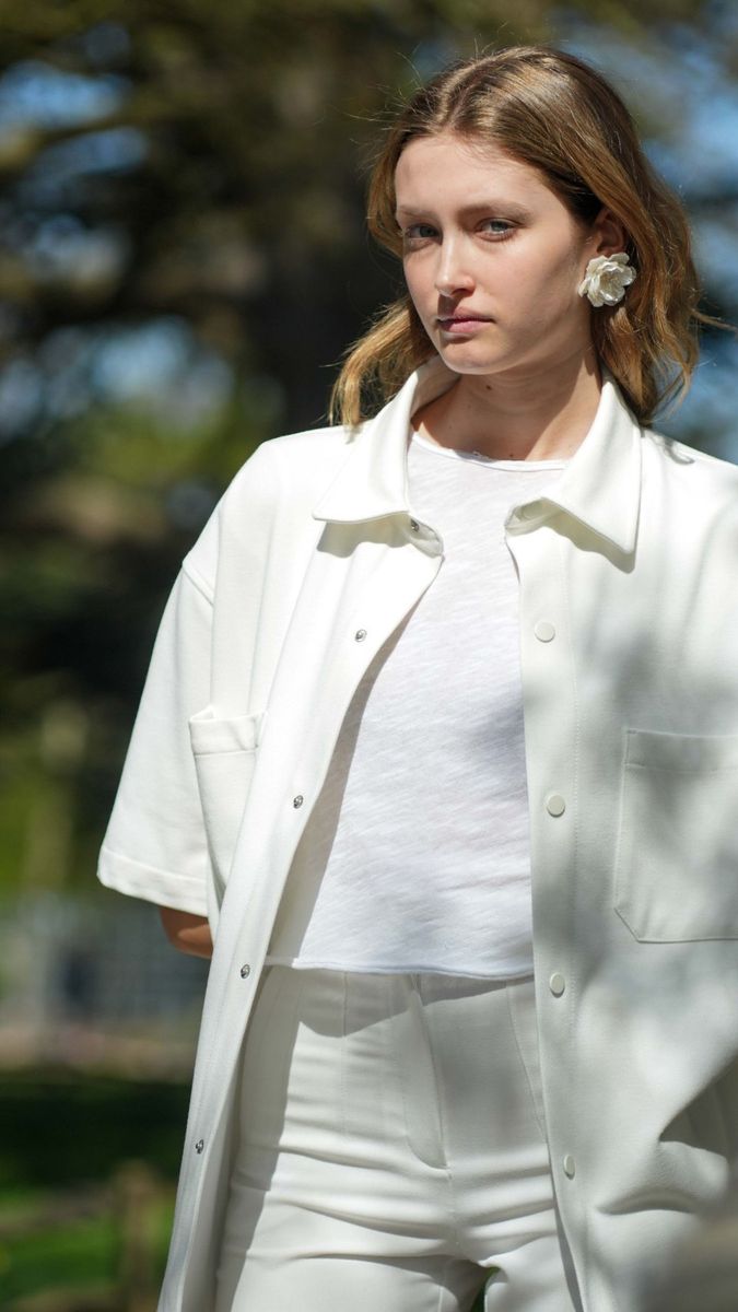 Alice in a white shirt jacket in dappled shade by a bridge rail, vertical frame, Linden Staub test