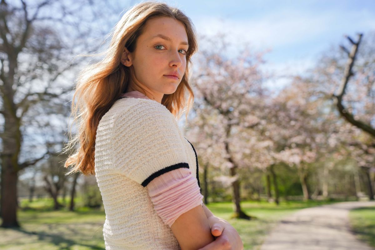 Alice Montemagno looks back over her shoulder on a blossom-lined path, Linden Staub test shoot in Richmond, London